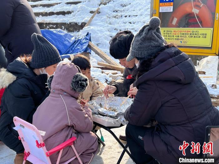 图为游客现场享用烤鱼。　刘旭 摄