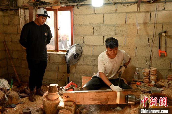 图为青年代表观看手工艺人制作木碗。　李嘉娴 摄