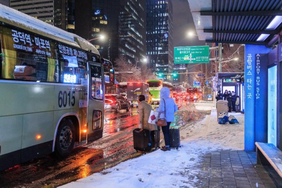 12月4日,在韩国首尔,人们在雪中候车。新华社发(朴晋泽摄)